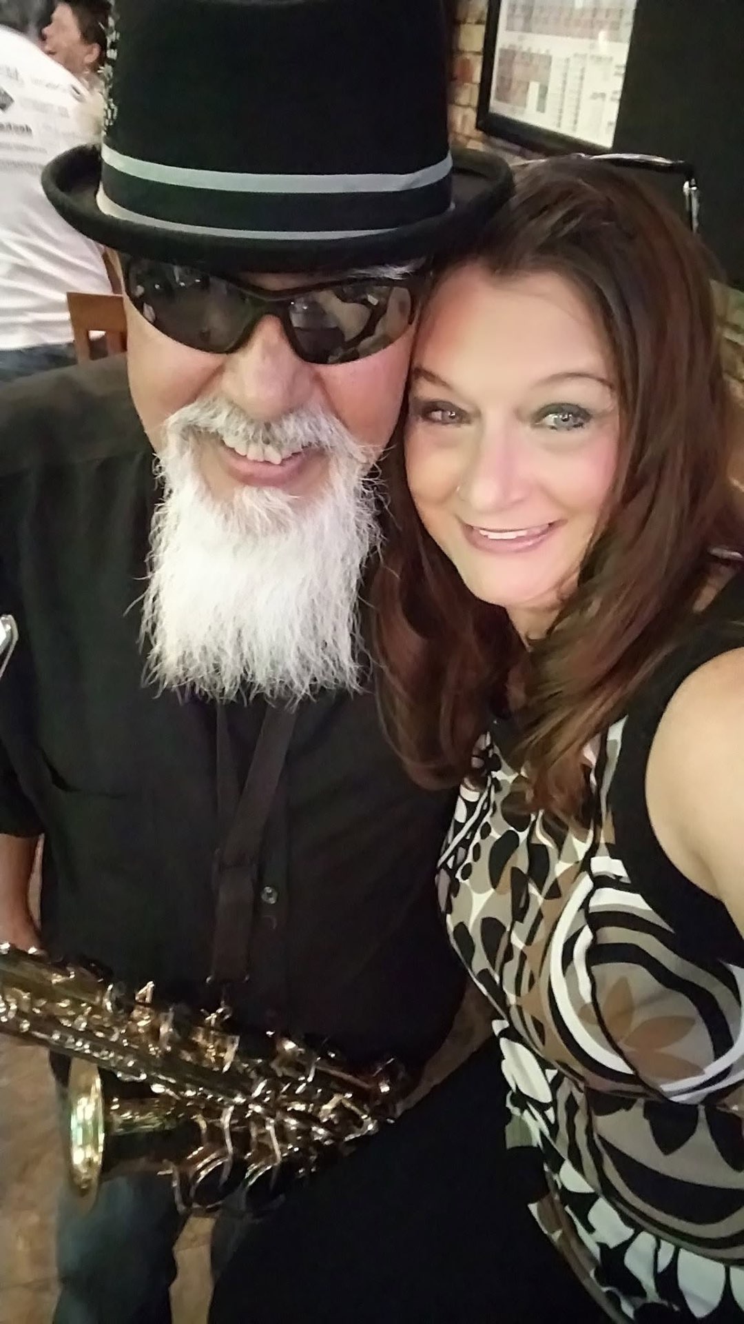 Laurie and Raul smiling together, saxophone in hand, before a show